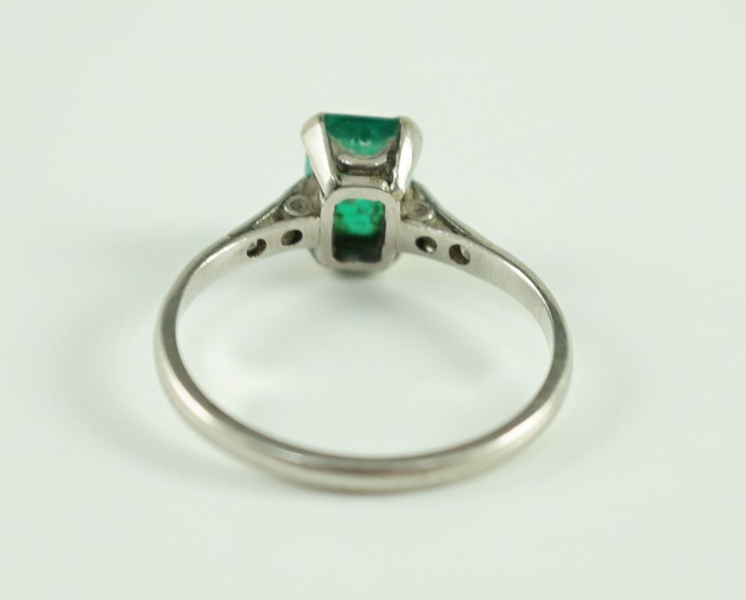 A white gold and single stone emerald ring, with six stone diamond set shoulders